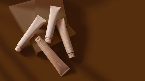 Four beige tubes of spf on a brown background