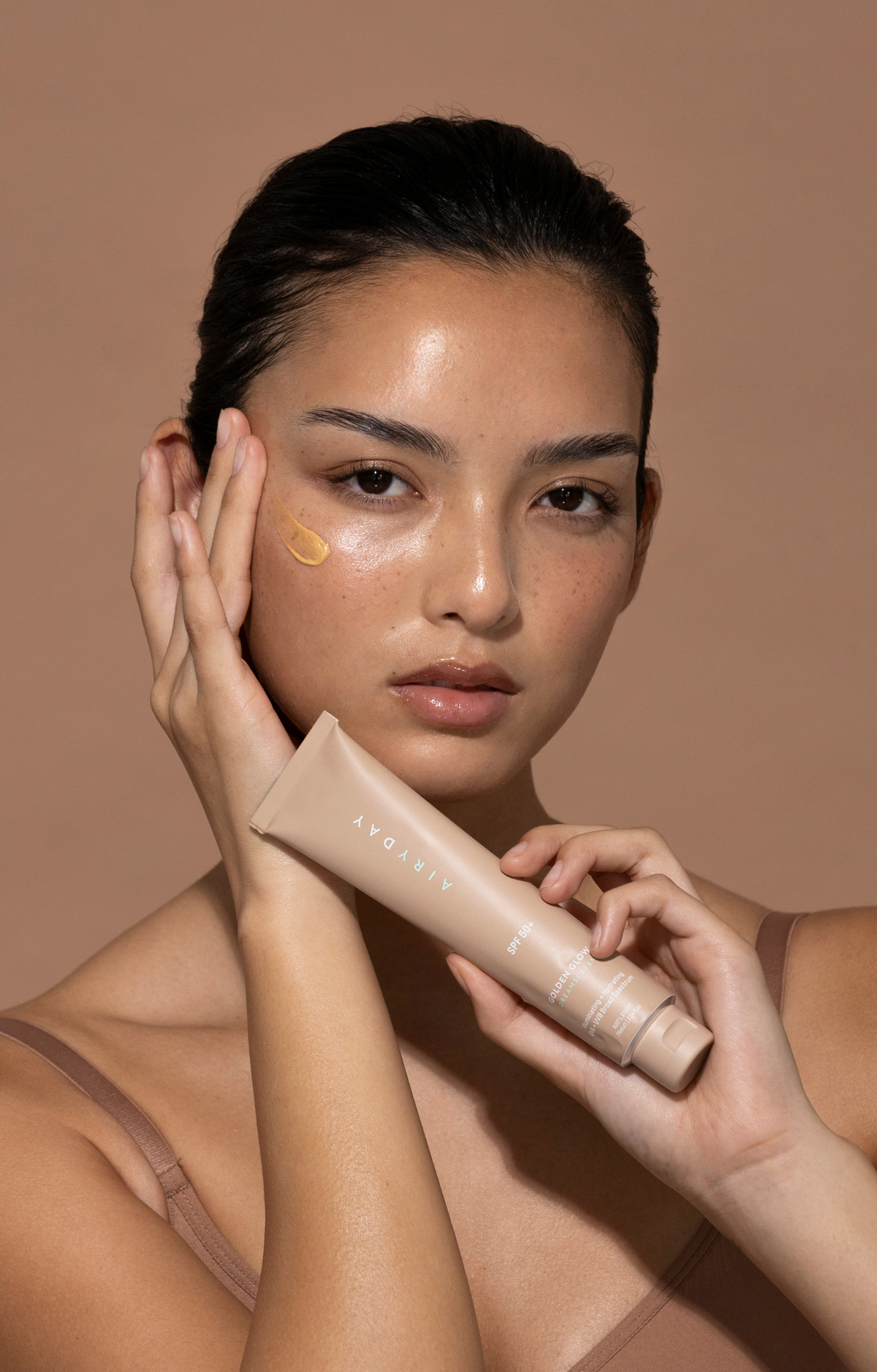 Model holding Golden Glow SPF50+ Dreamscreen